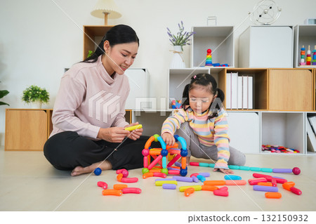 toddler girl and mother playing colorful magnetic construction toy at home toddler girl and mother playing colorful magnetic construction toy at home 132150932