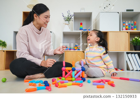 toddler girl and mother playing colorful magnetic construction toy at home 132150933