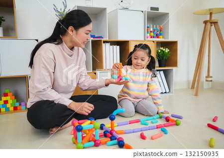 toddler girl and mother playing colorful magnetic construction toy at home 132150935
