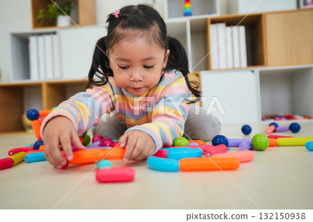 toddler girl playing colorful magnetic construction toy 132150938