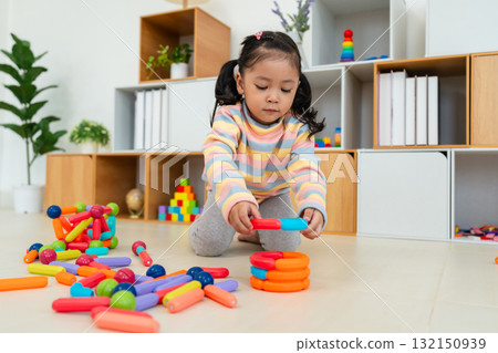 toddler girl playing colorful magnetic construction toy 132150939