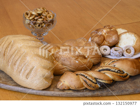 View of bread, loaf, bun with poppy seeds and bagels on a wooden table 132150977