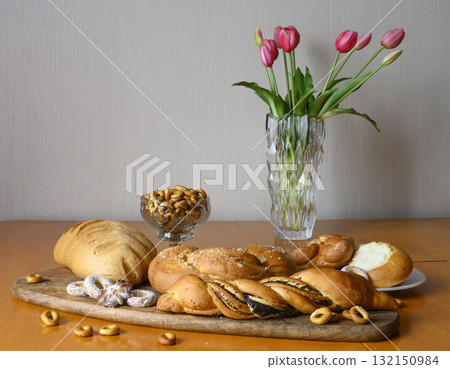 View of bread, loaf, bun with poppy seeds, bagels and flowers on a wooden table View of bread, loaf, bun with poppy seeds, bagels and flowers on a wooden table 132150984