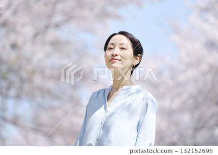 A woman taking a walk with the cherry blossoms in full bloom 132152696