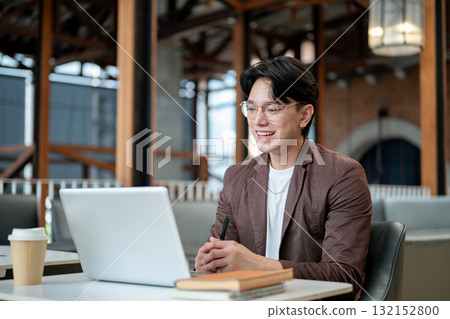 Brown suit asian man with glasses looking happily at a laptop. Online meeting or presentation. 132152800