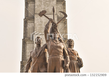 A statue with three people holding the hammer, sickle and caligraphy brush of North Korea A statue with three people holding the hammer, sickle and caligraphy brush of North Korea 132152909