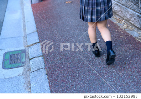 High school girl walking to and from school on a dark road after club activities on a cold day. High school student's skirt. Back view. No face. 132152983