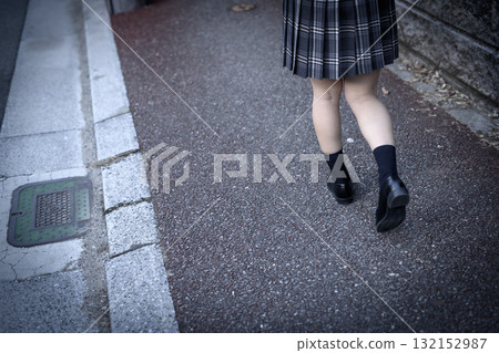 High school girl walking to and from school on a dark road for club activities on a cold day. High school student's skirt. Back view, no face. Negative image. 132152987