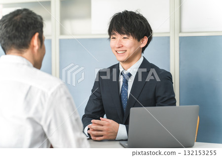A young Asian businessman serving customers in a showroom or business meeting space 132153255