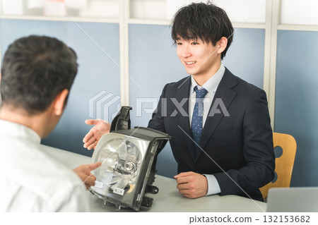 A male service front desk attendant and a male customer at the reception desk of an auto repair shop A male service front desk attendant and a male customer at the reception desk of an auto repair shop 132153682