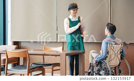 A restaurant employee serving a man in a wheelchair 132153917