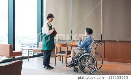 一名餐廳員工為一位坐輪椅的男士服務 一名餐廳員工為一位坐輪椅的男士服務 132153920