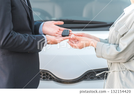 Salesman taking car keys from female customer, male salesman staff Salesman taking car keys from female customer, male salesman staff 132154420