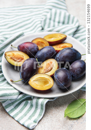 Fresh ripe plums with halves on plate for healthy eating 132154699