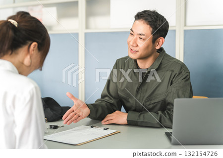 一名男性機械師和一名女顧客在汽車修理廠的接待處進行解釋、估價和建議。 132154726