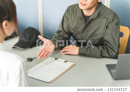 A male mechanic and a female customer giving explanations, estimates and proposals at the reception desk of an auto repair shop 132154727