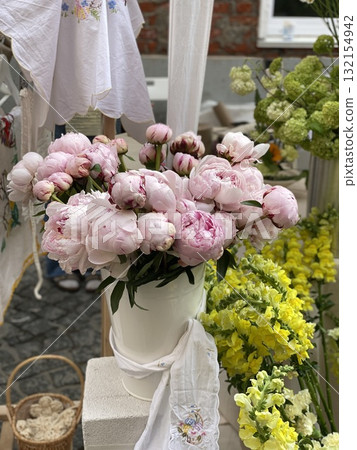 Peonies and flowers at outdoor market display with embroidered textiles Peonies and flowers at outdoor market display with embroidered textiles 132154942