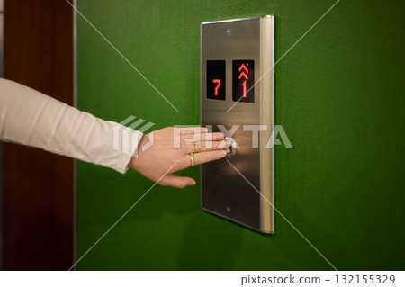 Pressing the elevator button in contemporary high rise buildings signifies modern urban convenience Pressing the elevator button in contemporary high rise buildings signifies modern urban convenience 132155329