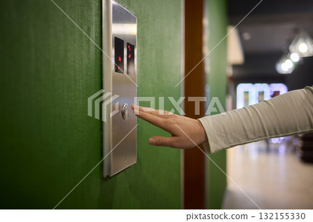 Pressing the elevator button in contemporary high rise buildings signifies modern urban convenience Pressing the elevator button in contemporary high rise buildings signifies modern urban convenience 132155330