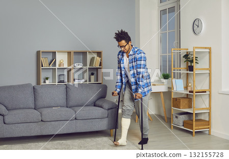 Disabled man using crutches for walking in living room Disabled man using crutches for walking in living room 132155728