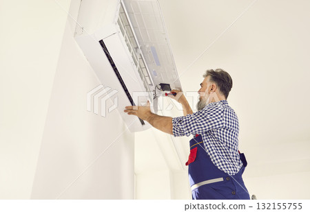 AC installation and maintenance service worker repairing or installing new air conditioner 132155755