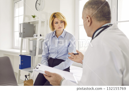 Mature male doctor consulting female patient in medical office Mature male doctor consulting female patient in medical office 132155769