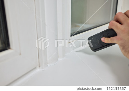 Sealing the corners of windows with caulk for achieving a perfectly neat and polished finish 132155867