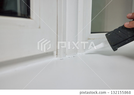 Sealing the corners of windows with caulk for achieving a perfectly neat and polished finish 132155868