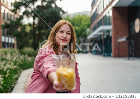 Curvy woman offering from bag of chips. 132155933