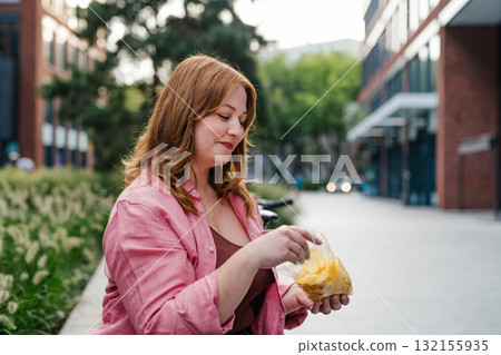 Plus size woman holding potato chip. Plus size woman holding potato chip. 132155935