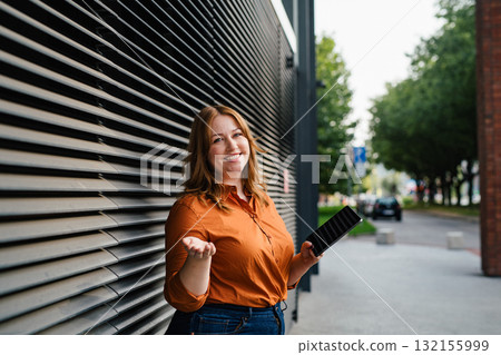 Plus size woman holding tablet, black background. 132155999
