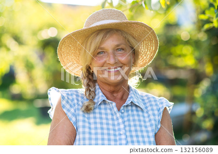 Happy elderly woman enjoying sunny day in garden. Happy elderly woman enjoying sunny day in garden. 132156089