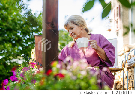 Senior woman taking care of plants in garden during peaceful morning. 132156116