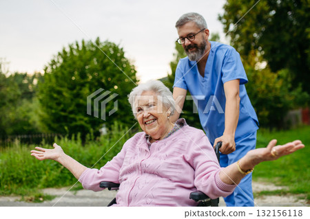 Senior patient and male nurse talking during walk outdoors. Senior patient and male nurse talking during walk outdoors. 132156118