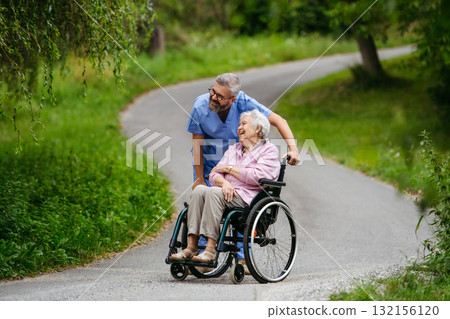 Male home nurse taking care of elderly woman in wheelchair. 132156120