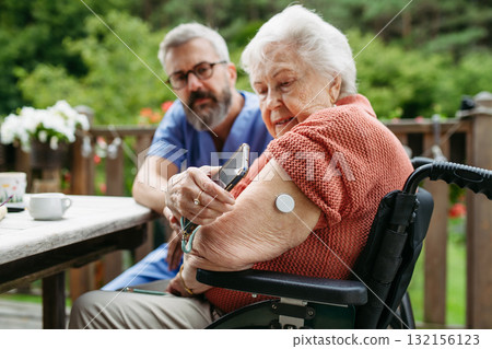 Home nurse checking glucose level of senior lady with smartphone. Home nurse checking glucose level of senior lady with smartphone. 132156123
