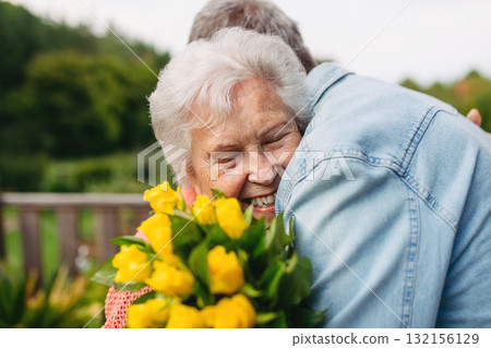 Mature son whishes a happy birthday to old mother, hugging her. Mature son whishes a happy birthday to old mother, hugging her. 132156129
