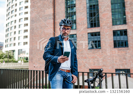 City commuter riding bike from work, reading text message on phone. City commuter riding bike from work, reading text message on phone. 132156160