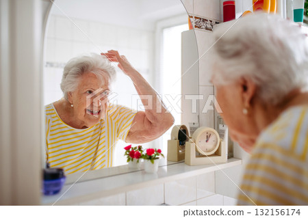 Senior woman combing her hair in bathroom. 132156174