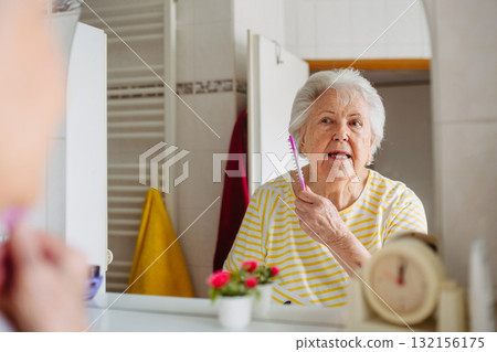 Senior woman combing her hair in bathroom. 132156175