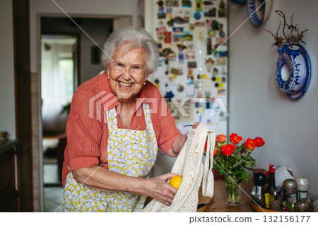 Senior lady in apron preparing fresh fruit at home. Senior lady in apron preparing fresh fruit at home. 132156177