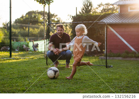 Little boy playing football with father in backyard. 132156216