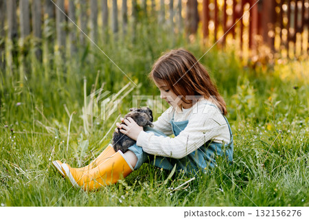Young girl gently cuddles a fluffy bunny in her arms. Young girl gently cuddles a fluffy bunny in her arms. 132156276