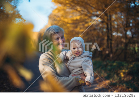 Grandma holding baby in warm embrace during fall season. 132156292