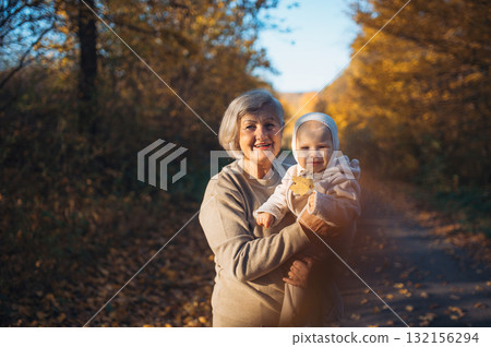 Grandma holding baby in warm embrace during fall season. 132156294