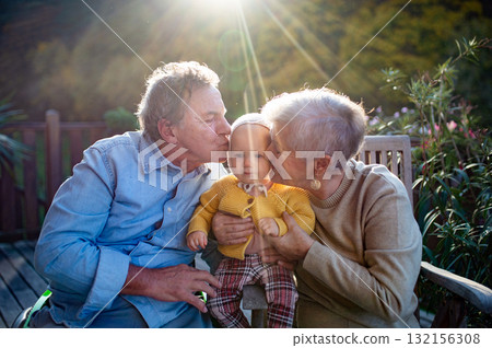 Grandparents holding baby in warm embrace during fall season. 132156308