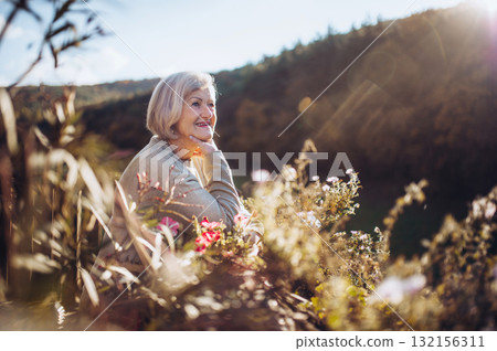 Portrait of smiling elderly lady relaxing on terrace during warm autumn day. Portrait of smiling elderly lady relaxing on terrace during warm autumn day. 132156311