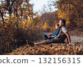 Dad and daughter in autumn nature, sitting on fallen leaves. 132156315
