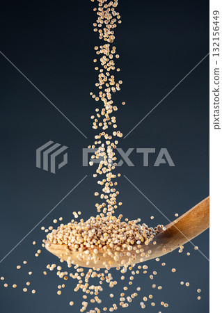 Dried whole Mustrad seeds fall from above onto a wooden spoon, ideal for cooking ingredients and organic food photography 132156449