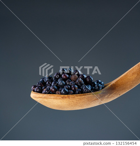 Fresh dried juniper berries in natural wood ladle, ideal for culinary herbs and aromatic cooking ingredient concepts 132156454
